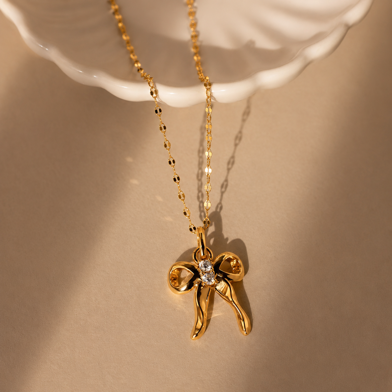 Gold necklace with a bow-shaped pendant on a beige background
